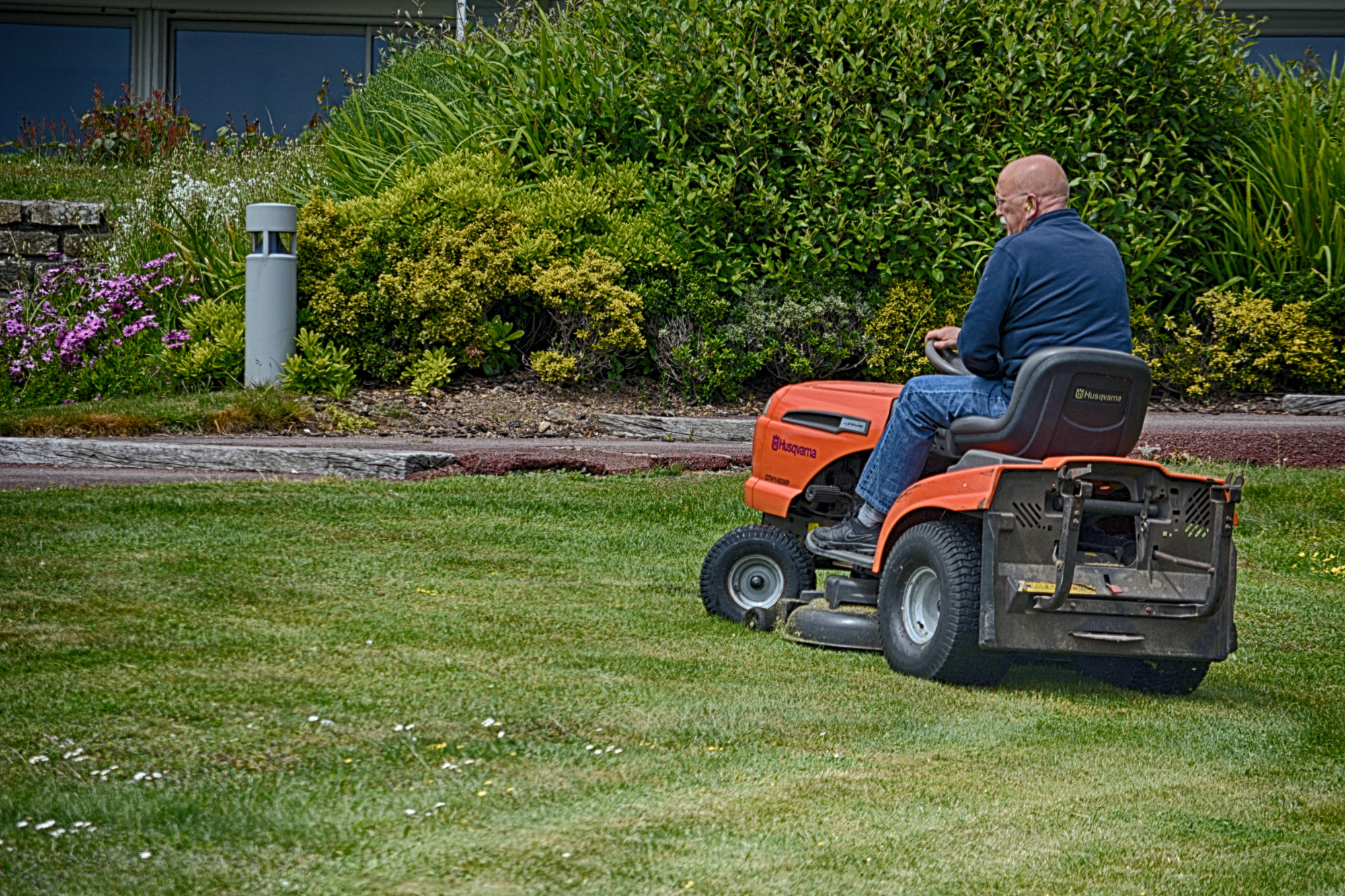 A landscaper at work on a riding mower
